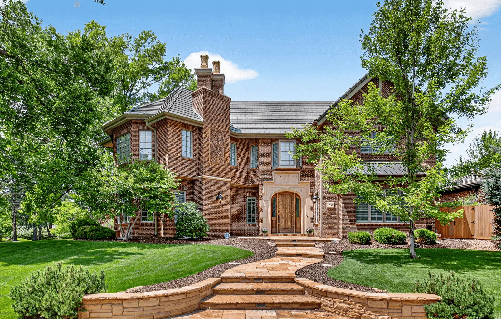 Beautiful two-story luxury brick house with manicured lawn, stone pathway, and bright summer sky — ideal hero image for real estate photography services. Beautiful two-story luxury brick house with manicured lawn, stone pathway, and bright summer sky — ideal hero image for real estate photography services.