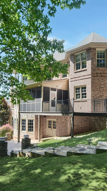 Two-story back exterior of a home featuring a tiered deck and a covered porch, an example of quality backyard photography.