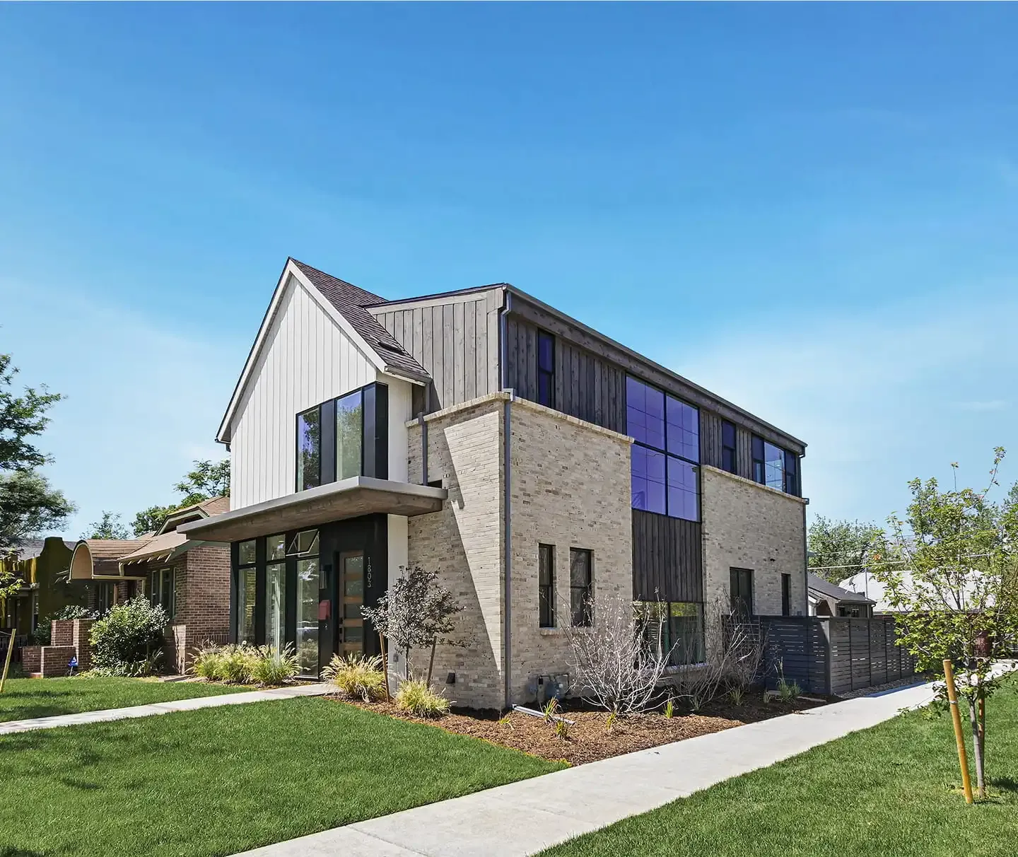Modern brick and board home under a blue sky
