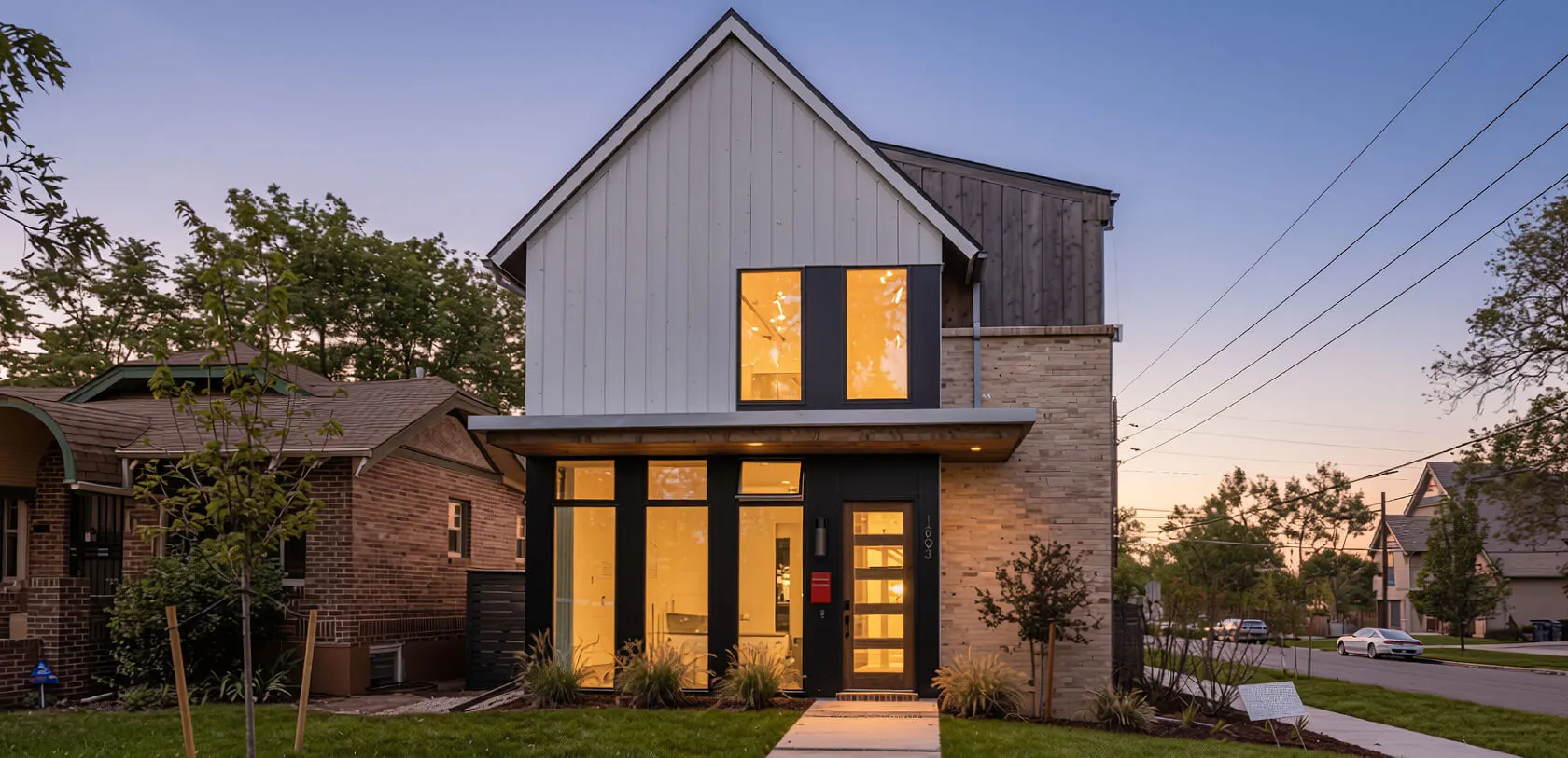 Modern farmhouse at twilight with warm light glowing from the windows