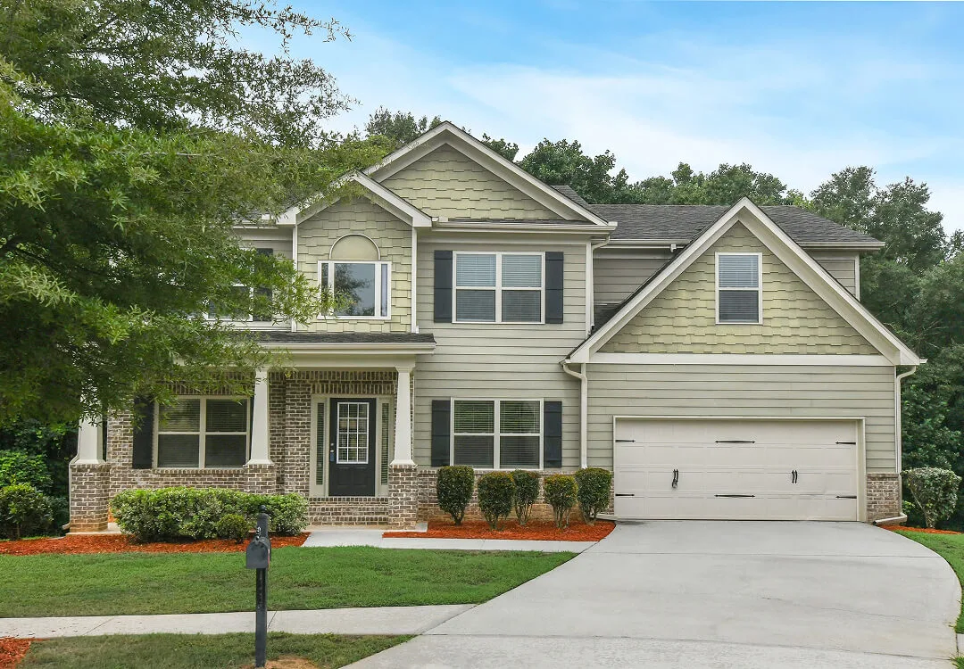 Front view of a two-story traditional home with stone accents and a prominent garage, showing professional curb appeal photography.