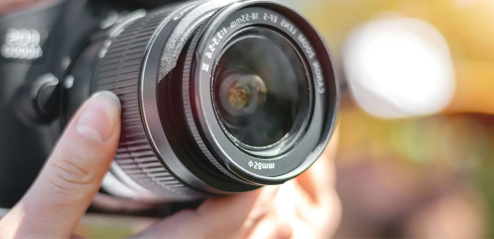 Close-up shot of a photographer's hand adjusting the focus ring on a DSLR camera lens, representing professional real estate photography.