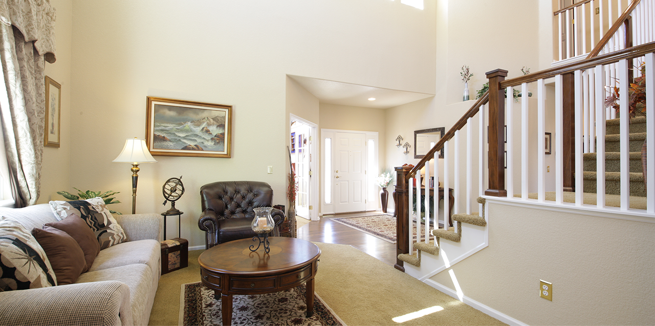 Home entryway and staircase landing area featuring dark wood railing, decorative console table, and bright natural lighting.