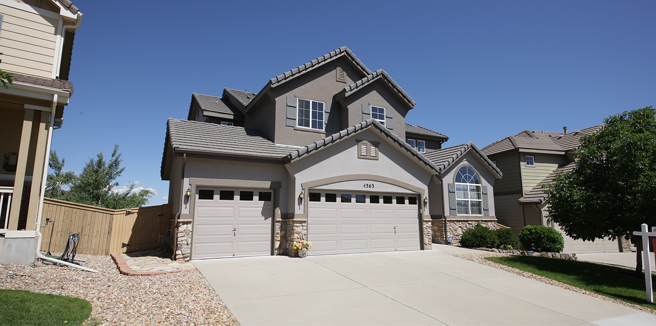 Professional real estate photo of a modern suburban home in Atlanta with gray siding, stone accents, and a spacious three-car garage.