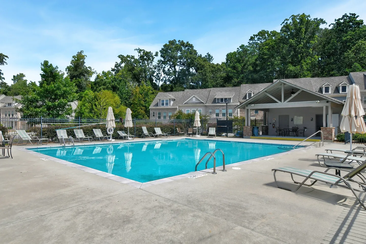 Wide shot of a clean, resort-style community swimming pool and lounge area, excellent for amenity photos.
