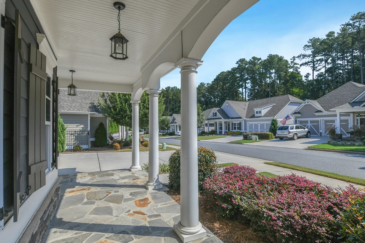 Exterior covered patio with columns and a view of a landscaped suburban street.