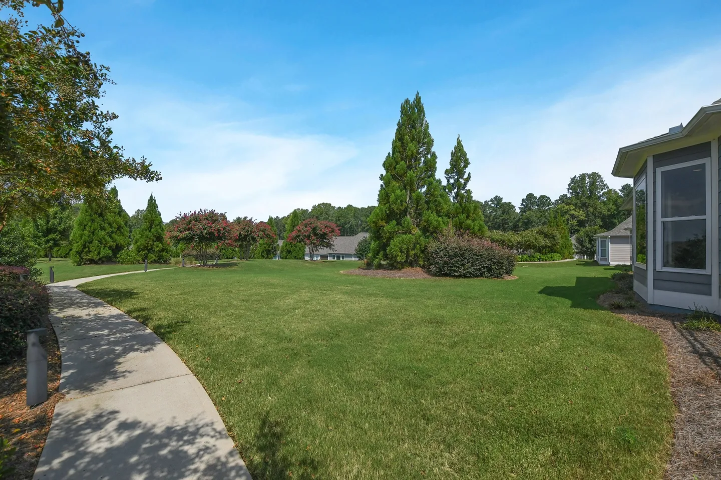 Wide-angle photograph of a spacious, level, and well-maintained green backyard behind a house.