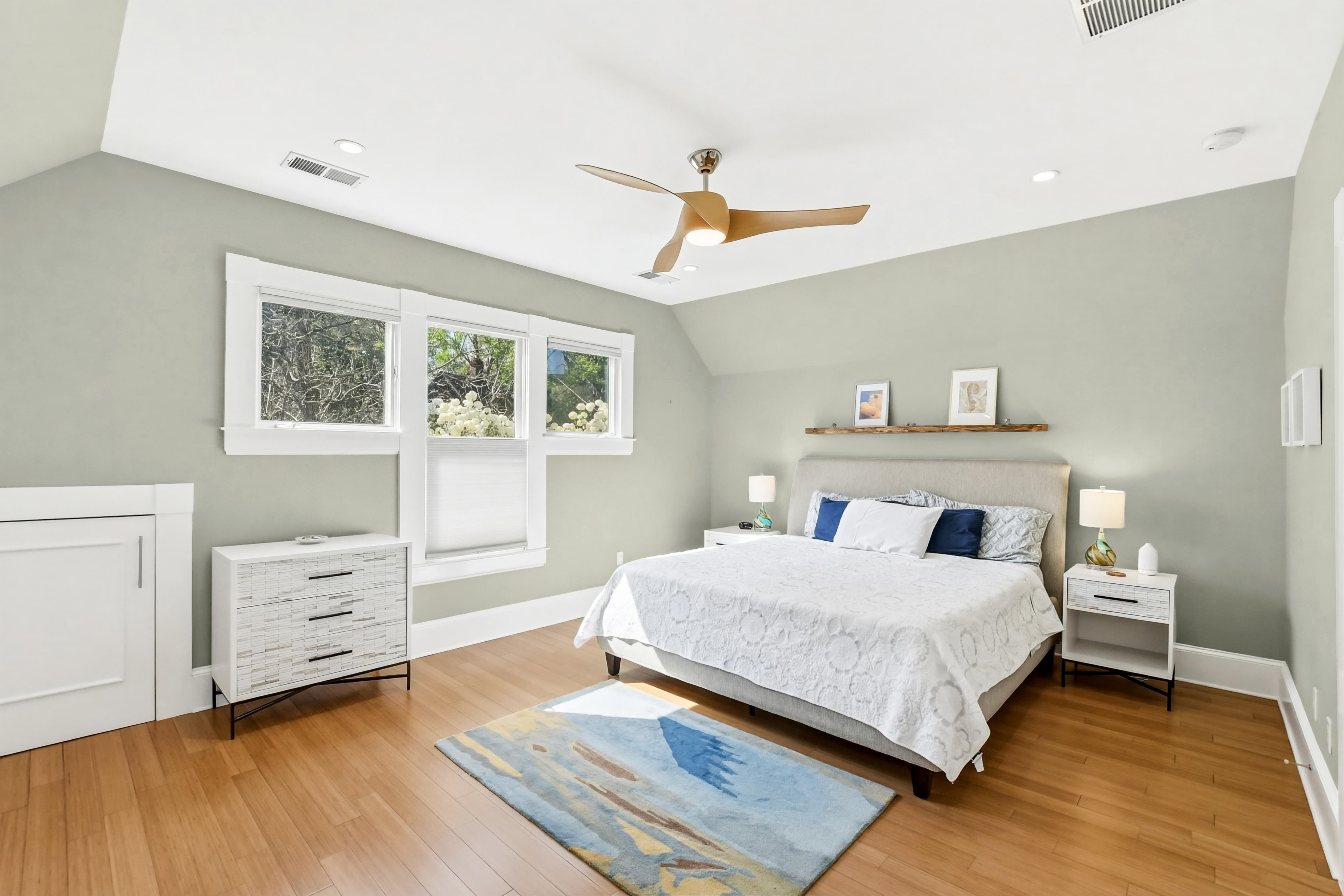Upstairs bedroom with vaulted ceiling, sage green walls, bamboo floors, and a row of three windows
