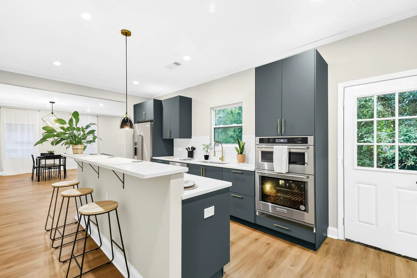 Kitchen with navy flat-panel cabinets, breakfast bar island, wall oven, and an open view to the dining area