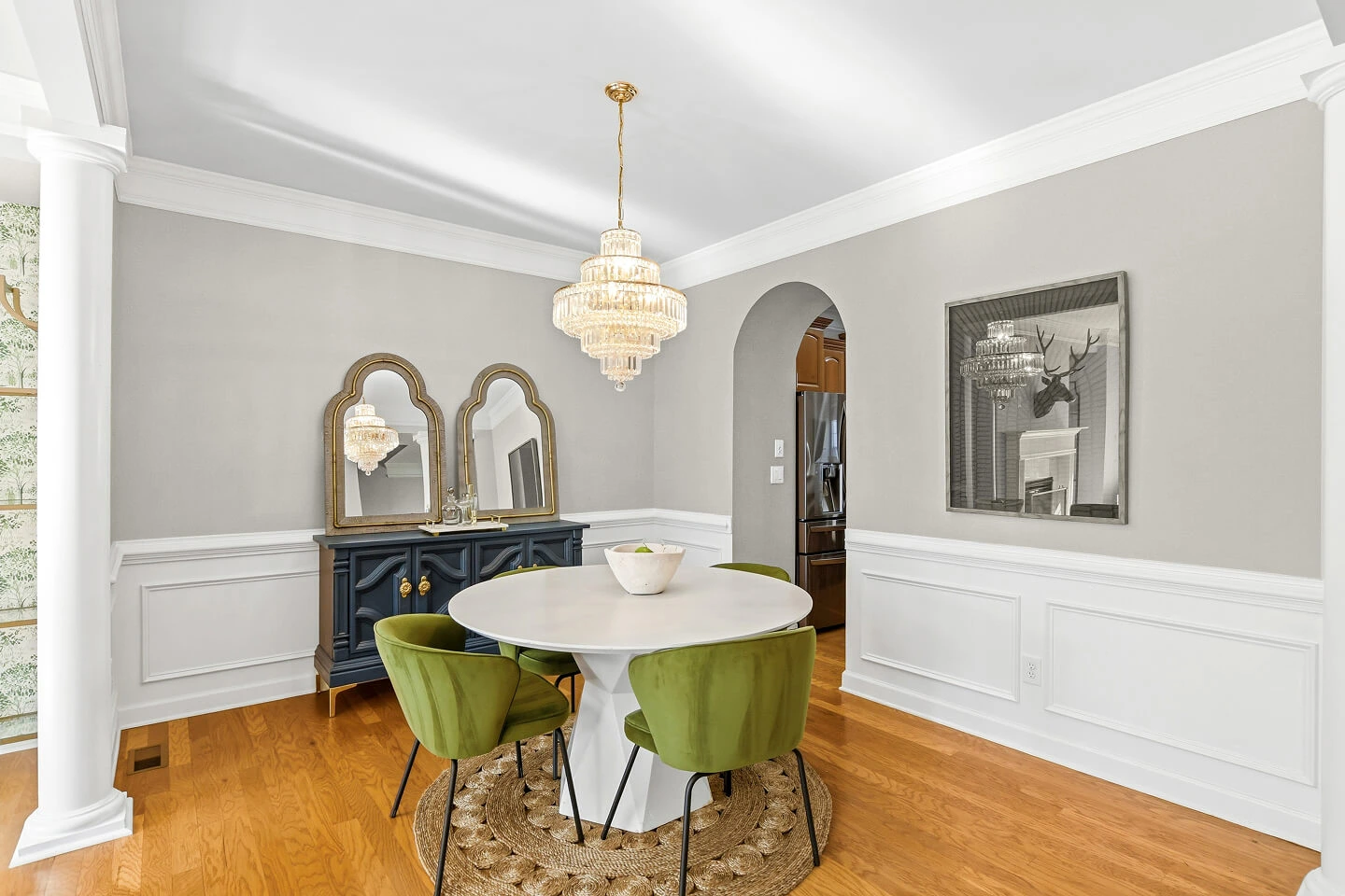 Formal dining room with crystal chandelier, wainscoting, arched doorway, and round pedestal table