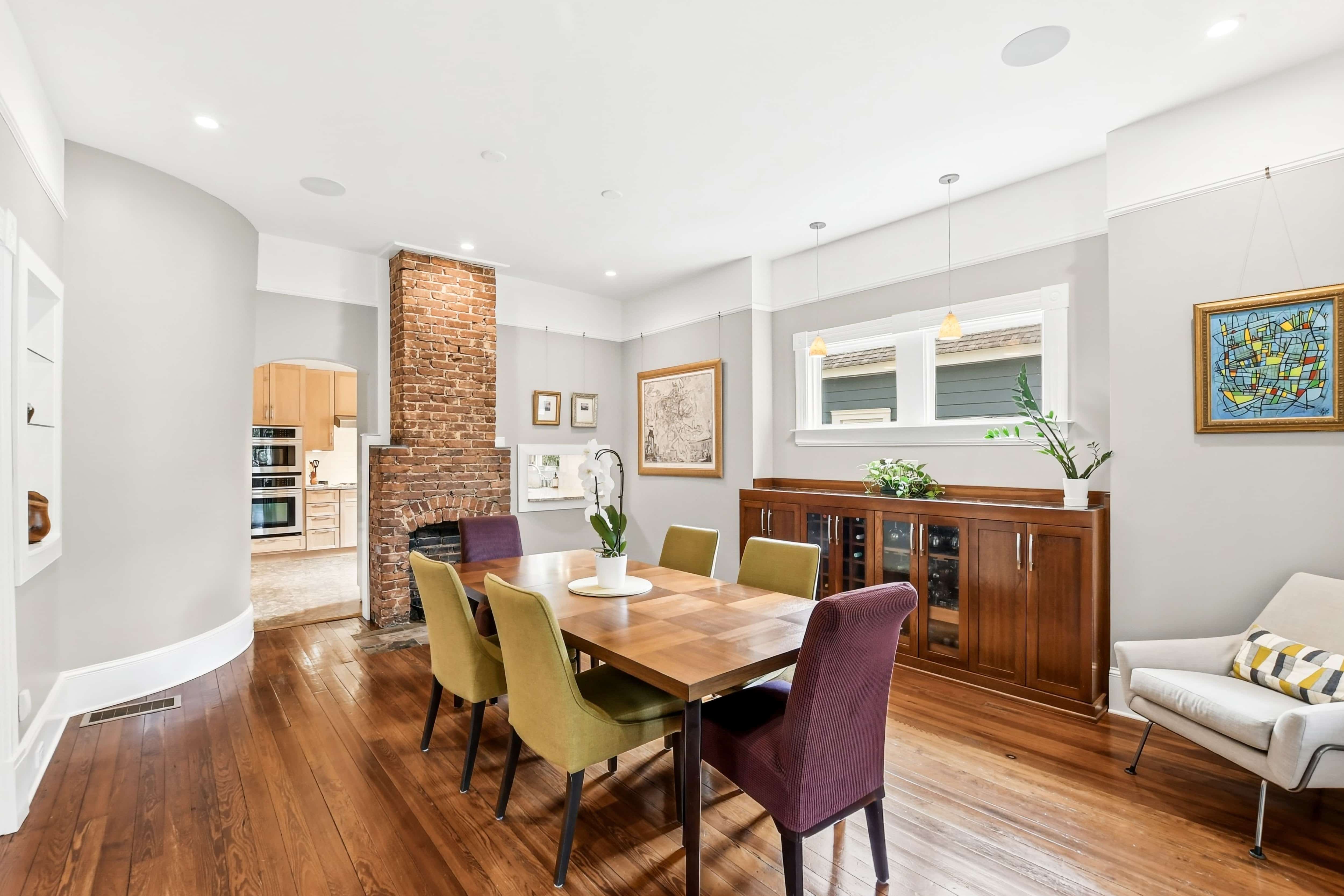 Dining room with exposed brick fireplace, built-in wood buffet with wine storage, and original hardwood floors