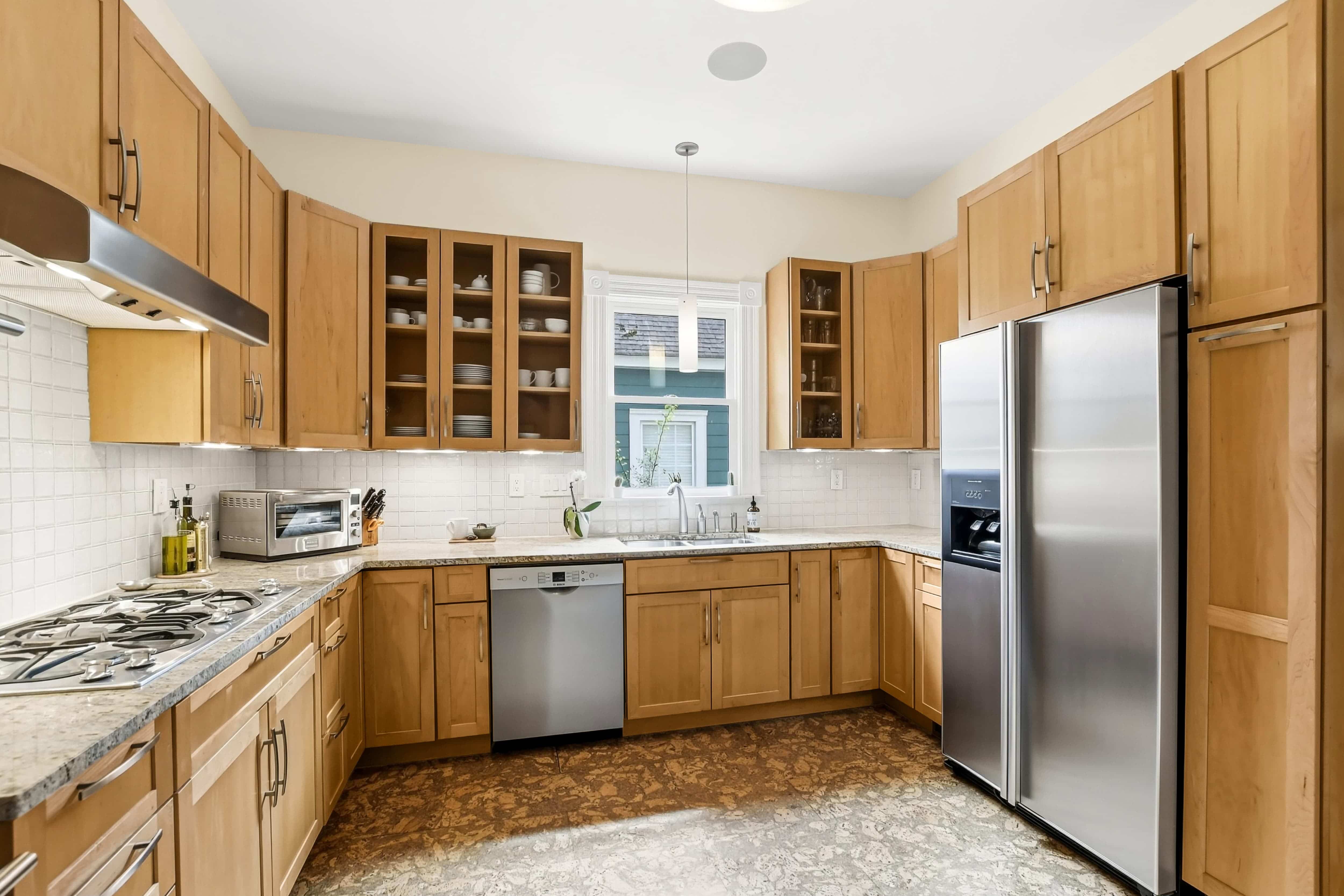 U-shaped kitchen with maple shaker cabinets, granite countertops, gas cooktop, and stainless steel appliances