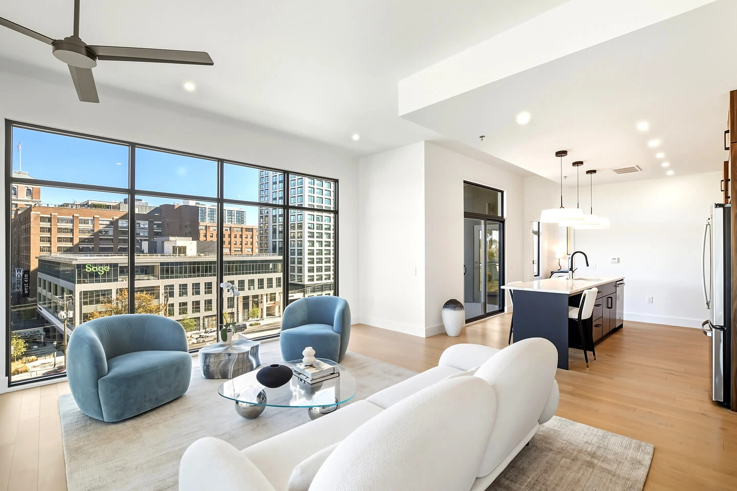 Modern living room with floor-to-ceiling windows, city views, and an open kitchen with island seating