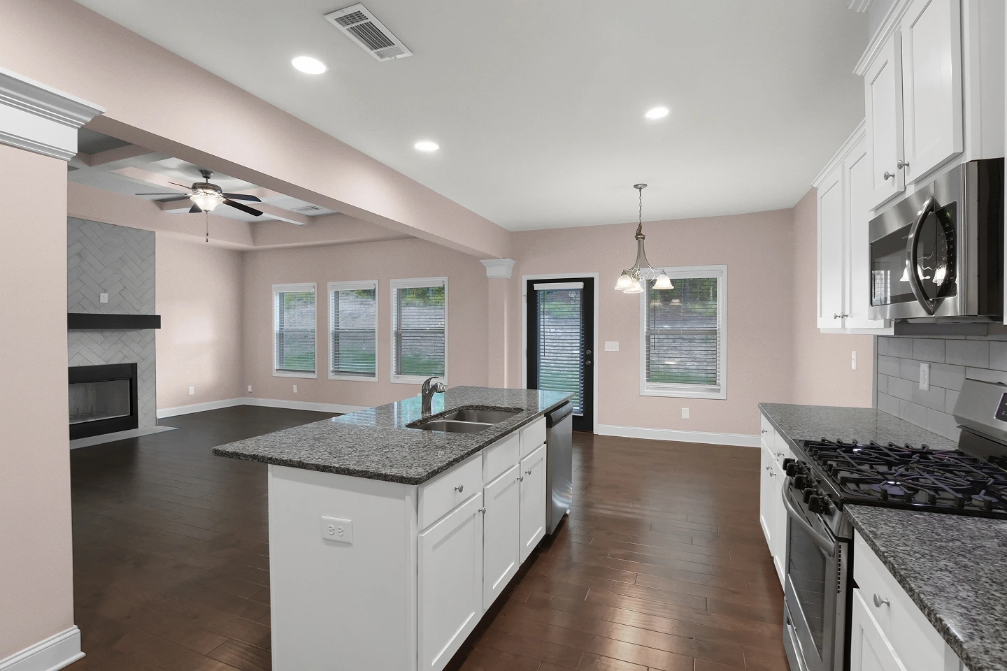 Wide shot of a large, well-lit kitchen with extensive white cabinets and a big island, captured by Blue Dot Photos in Atlanta.