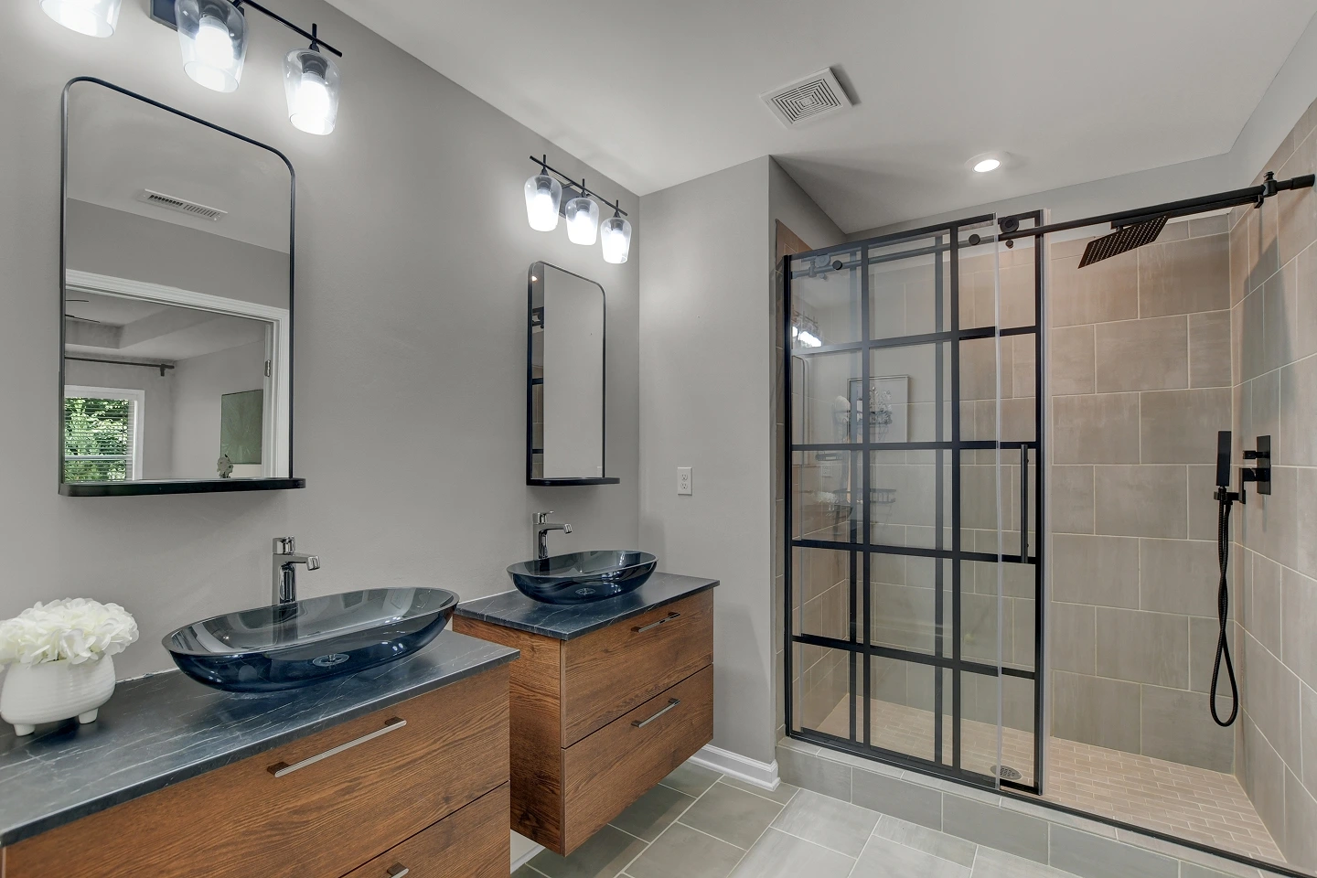 Contemporary bathroom with a double vanity, large mirror, and a walk-in shower with a glass enclosure.