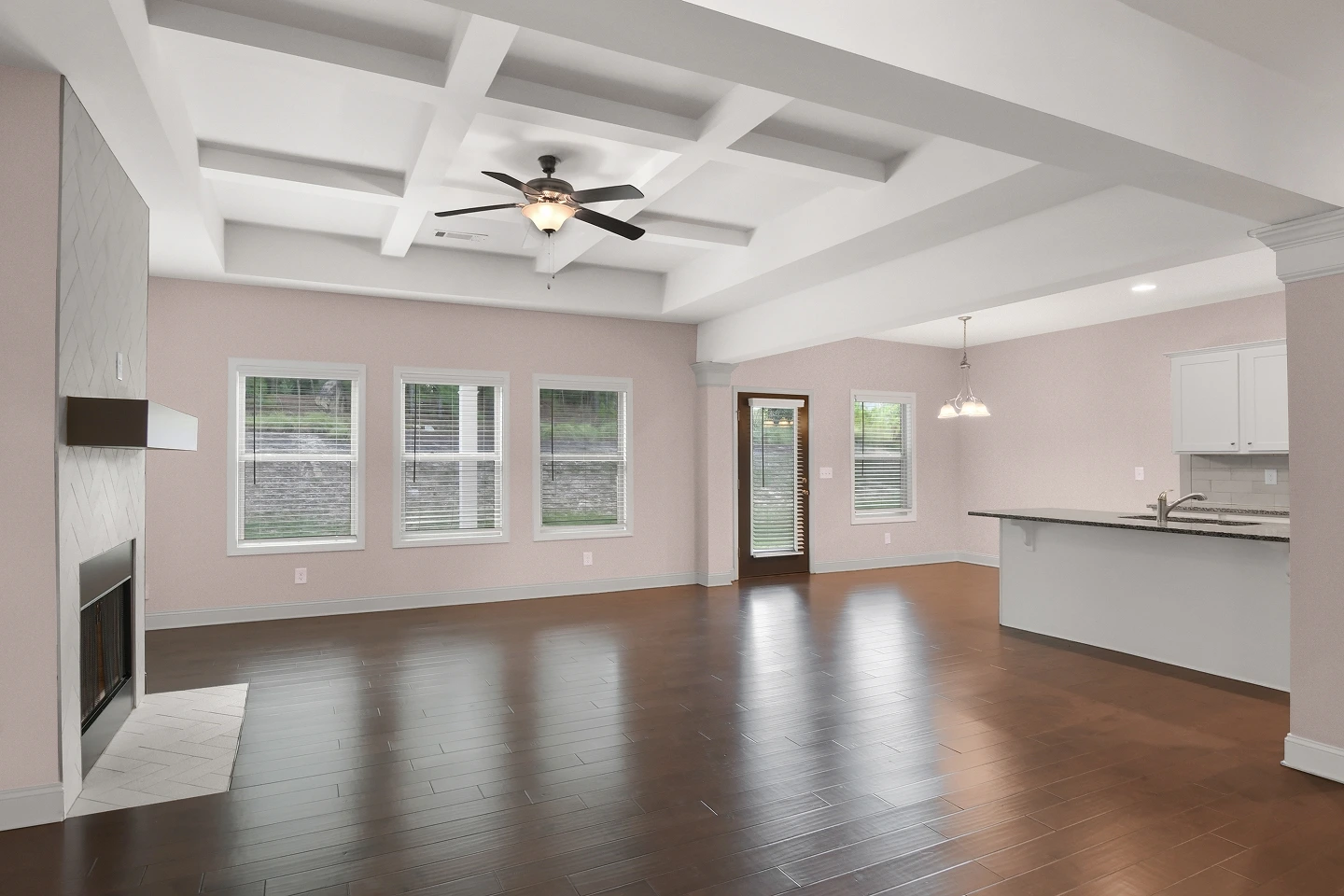 Empty living space with a detailed tray ceiling and ceiling fan, showcasing interior architectural features.