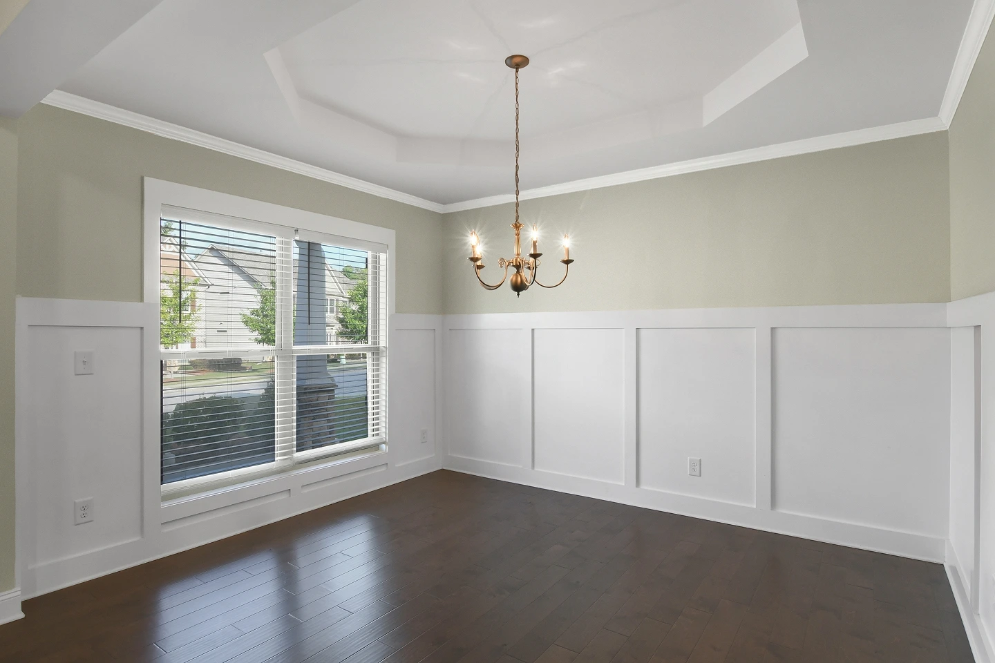 Empty living room with dark wood floors, white walls, and a prominent tray ceiling, ideal for virtual staging.