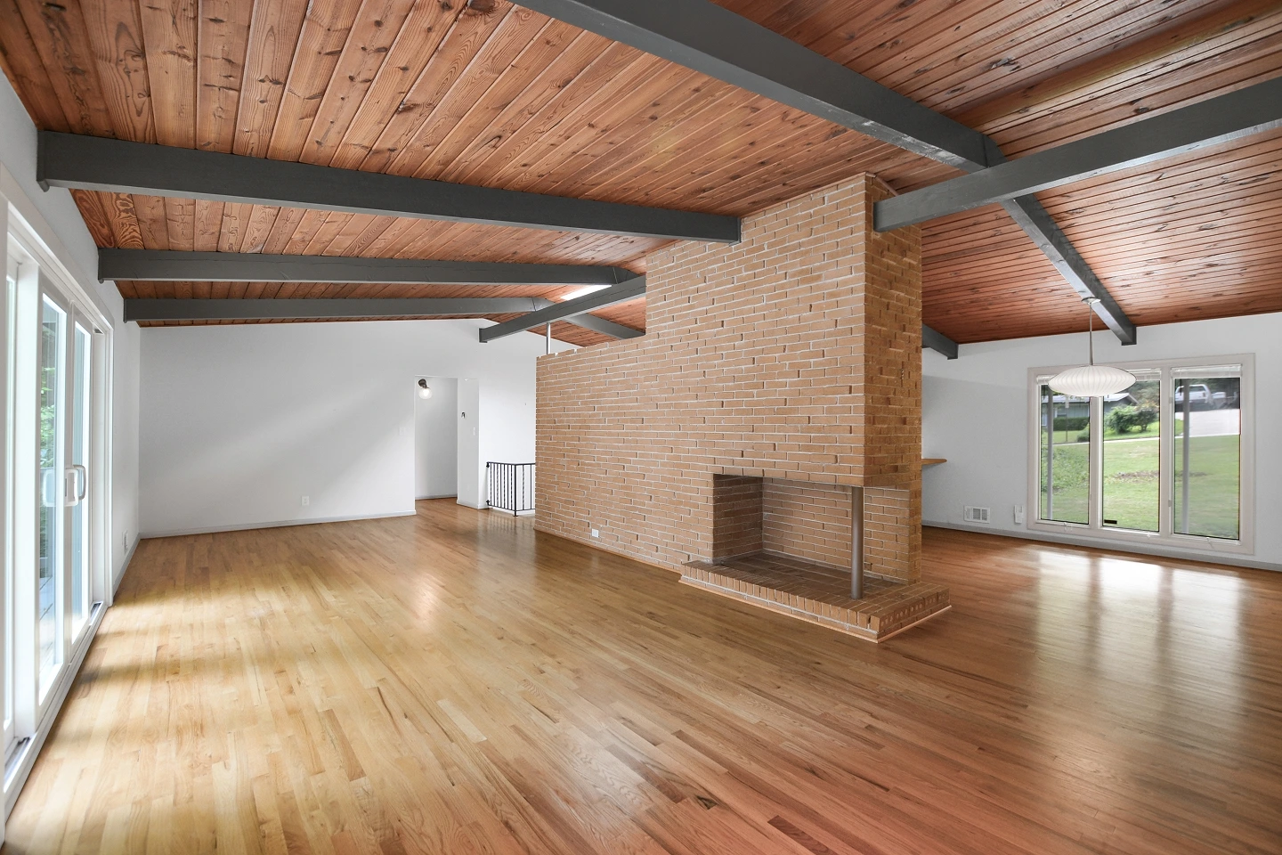 Empty industrial-style room with glossy hardwood floors and exposed wood ceiling beams.