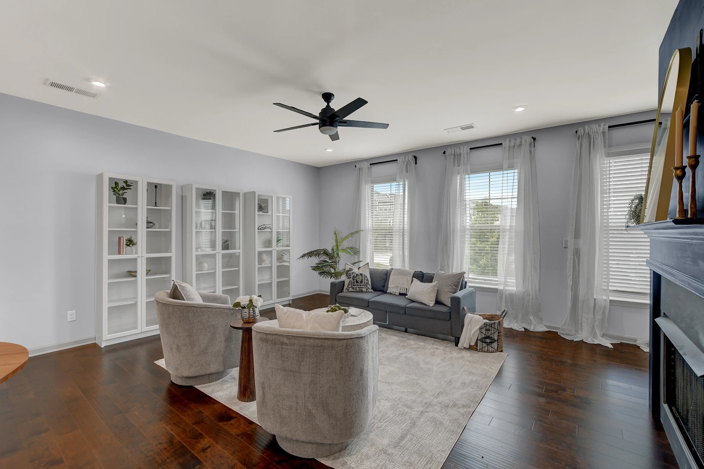Tastefully staged master bedroom with dark floors and a ceiling fan, a clean real estate photograph.