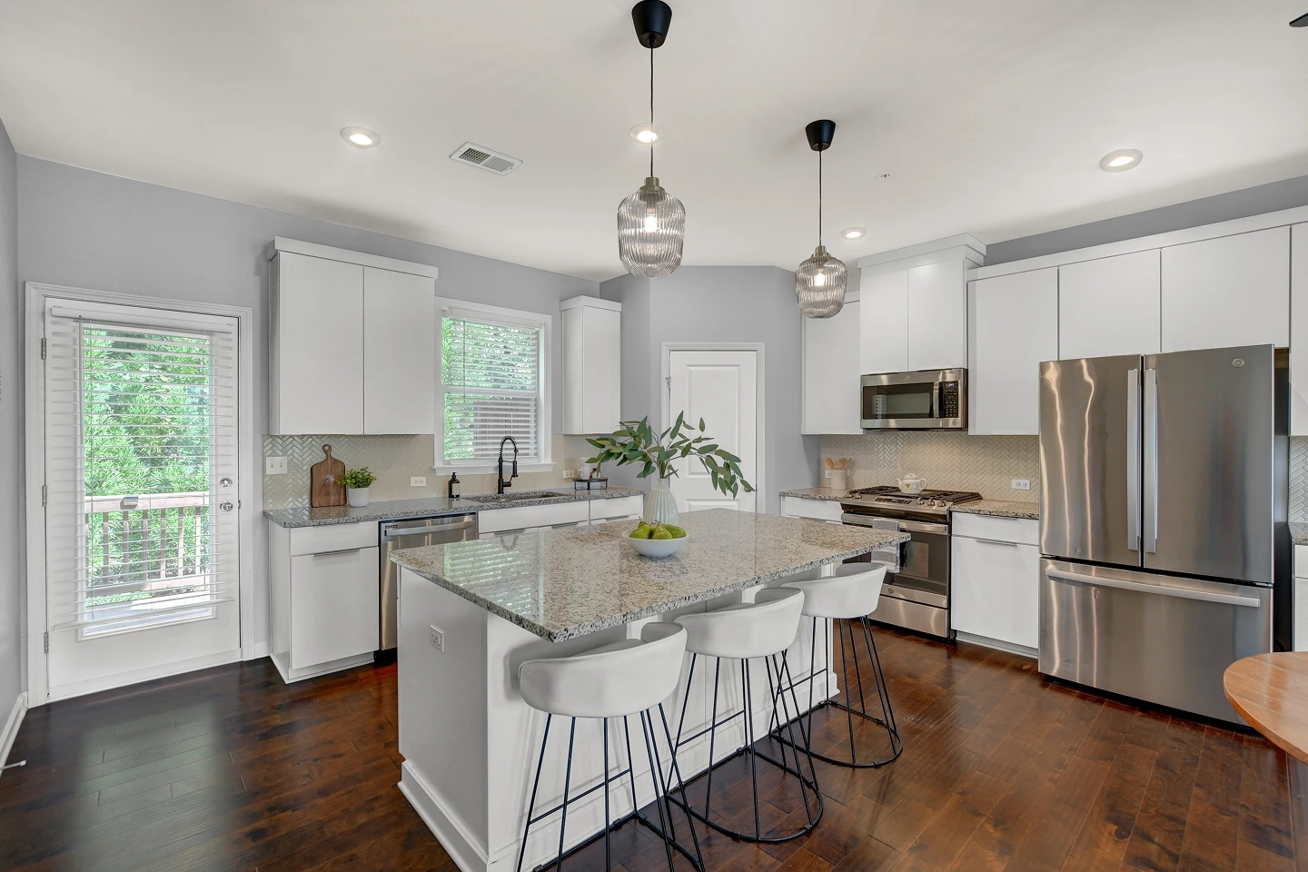 Wide-angle view of a modern kitchen with dark wood floors and open floor plan, showing flow and spatial context.
