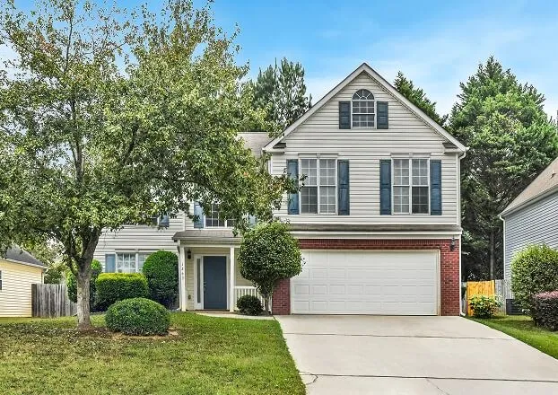 High-quality exterior photograph of a two-story traditional home in Atlanta featuring light siding, a prominent garage, and strong curb appeal.