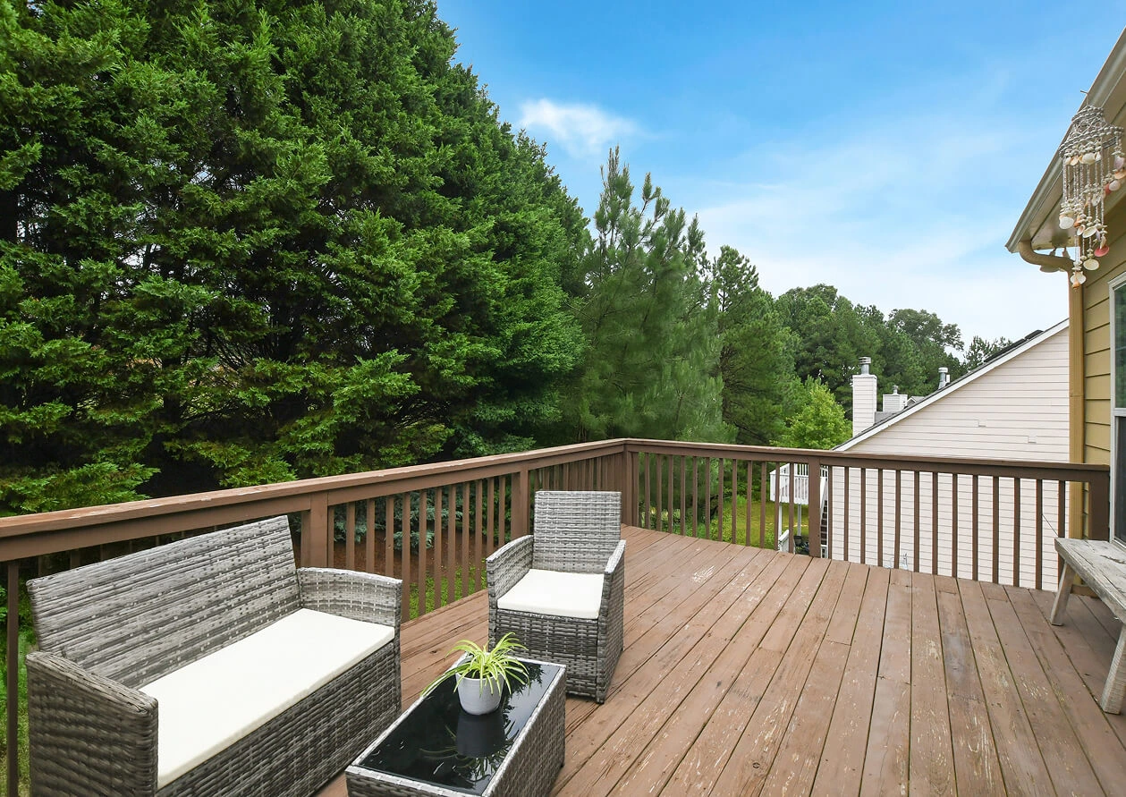 Elevated wooden deck furnished with a white bench, captured on a sunny day to highlight outdoor entertaining potential.