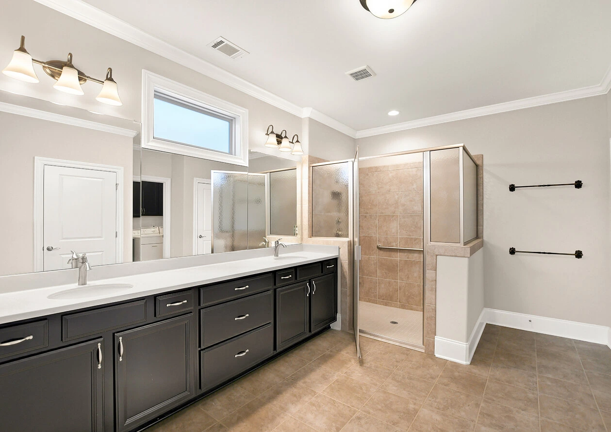 Contemporary bathroom with a double vanity featuring black cabinets, white countertops, and a glass walk-in shower.